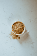 Green-Lipped Mussel Powder supplement in white container with measuring scoop on marble surface